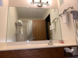 a bathroom with a large mirror over a sink at Super 8 by Wyndham Germantown/Milwaukee in Germantown