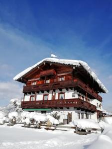 ein großes, schneebedecktes Holzgebäude in der Unterkunft Gästehaus Marianndl in Schönau am Königssee