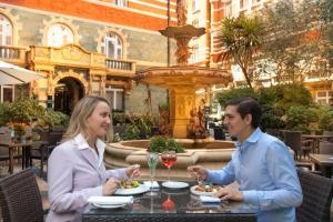 
a man and woman are eating at a restaurant at St. James' Court, A Taj Hotel, London in London
