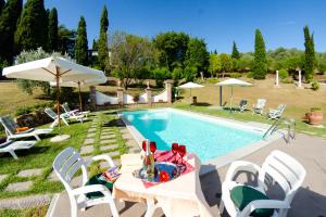 a swimming pool with a table and chairs next to it at Villa al Borghetto in Uzzano