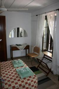 a bedroom with a bed and a chair and a window at The Bunch Of Grapes Inn in Pissouri