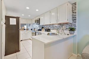uma cozinha com armários brancos e um frigorífico de aço inoxidável em Inlet Reef em Destin