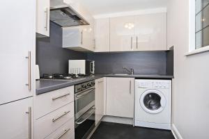 a kitchen with white cabinets and a washer and dryer at ALTIDO 2BR Apartment with Free Parking, near The Royal Mile in Edinburgh