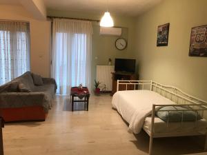 1 dormitorio con cama, sofá y TV en Διαμέρισμα 65 τμ στην καρδιά της πόλης, en Tripolis