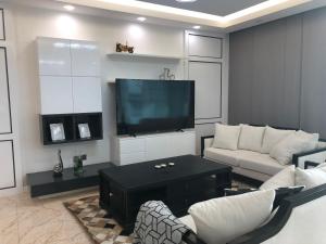 a living room with a couch and a flat screen tv at Saxophone Suites (Family Only) in Amwaj Island