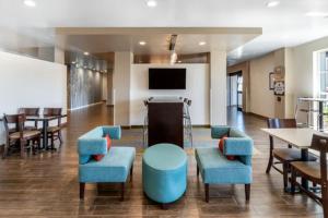 - un hall avec des tables et des chaises bleues et une télévision dans l'établissement MainStay Suites Denver International Airport, à Denver