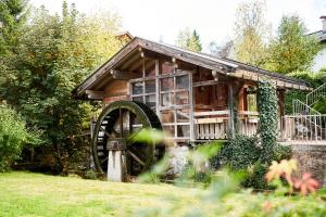 a wooden cabin with a large wheel in the yard at RosaMunde Apartments in Leutasch
