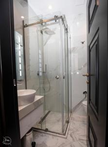 a bathroom with a glass shower and a sink at Hotel Kloest in Durrës