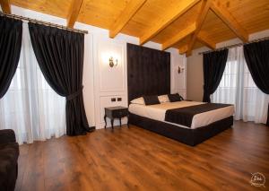 a bedroom with a bed with black curtains and wooden floors at Hotel Kloest in Durrës