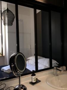 een badkamer met een spiegel met een wastafel en een bed bij LE NID DES ROIS, à 2 pas de la Cathédrale in Reims