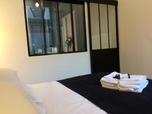een slaapkamer met een bed met witte lakens en een spiegel bij LE NID DES ROIS, à 2 pas de la Cathédrale in Reims