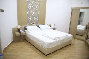 1 dormitorio con cama blanca y espejo en SAJ Farm Inn en Ibrā