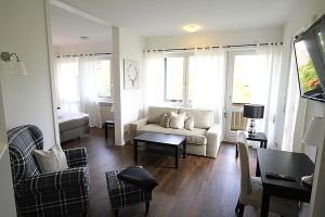 een woonkamer met een bank, stoelen en ramen bij Hotel garni - Chiemsee-Pension-Seebruck in Seebruck