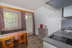 a kitchen with a table and two chairs and a sink at Ferienwohnungen Petschnig 2 in Drobollach am Faaker See