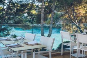 a table with white chairs and a view of the water at Iberostar Waves Pinos Park in Font de Sa Cala