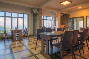 un comedor con mesas, sillas y ventanas en 7 Sisters Falls View Inn, en Cherrapunji