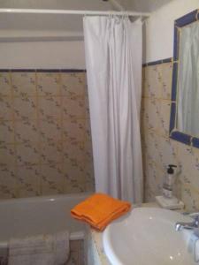 a bathroom with a sink and a bath tub with a orange towel at El Tinao in Yegen