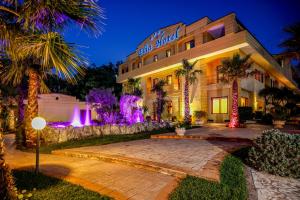 BuccinoにあるElia Hotelのヤシの木と紫の光が印象的な外観