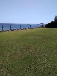 un campo de hierba con el océano en el fondo en Villa Adelina, en Porto Columbu - Perdʼe Sali