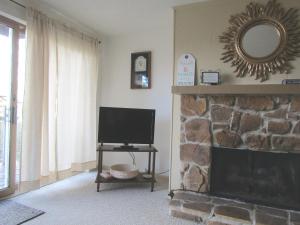 sala de estar con TV y chimenea en Cozt Downstairs Skyleaf D1 Condo, en Sugar Mountain