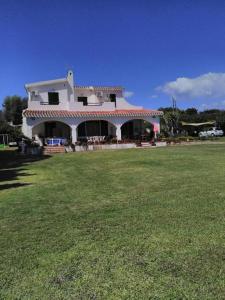 una grande casa bianca con un grande cortile erboso di Villa Adelina a Porto Columbu - Perdʼe Sali