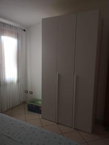 ein Schlafzimmer mit einem weißen Schrank und einem Fenster in der Unterkunft Bilocale in Residenza con Vista Mare - B9 in Aglientu