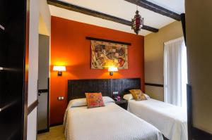 two beds in a room with orange walls at La Flor De Al-Andalus in Merida