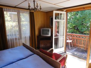 una camera con letto e un balcone con TV di Hotel Cima a Zermatt