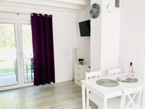 a white dining room with a table and a window at Lawendowe Domki Dziwnówek in Dziwnówek