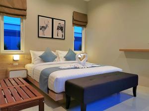 a bedroom with a large bed with a bench and windows at The Apex private pool villa Krabi in Krabi