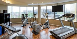 a gym with several cardio machines in a room with windows at Sofitel Luxembourg Europe in Luxembourg