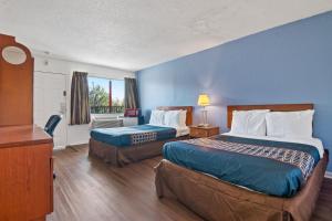 a hotel room with two beds and a window at Economy Lodge Portsmouth in Portsmouth