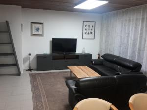 a living room with a black leather couch and a television at Haus Rangau für Ferien-und Messen in Wendelstein