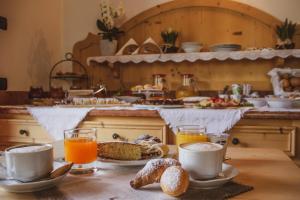 a table with cups and plates of food and orange juice at Hotel Garnì La Soldanella in Madonna di Campiglio