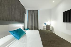 ein Hotelzimmer mit einem großen Bett mit einem blauen Kissen in der Unterkunft Amura Alcobendas in Alcobendas