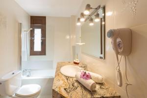 a bathroom with a toilet, sink, mirror and bath tub at Hotel Restaurant Castellarnau in Escaló