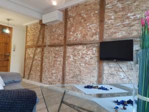 sala de estar con pared de ladrillo y mesa de cristal en Mirador de Zocodover, en Toledo