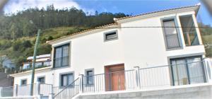 ein weißes Gebäude mit einem Balkon und einem Berg in der Unterkunft The Rose House in Arco da Calheta