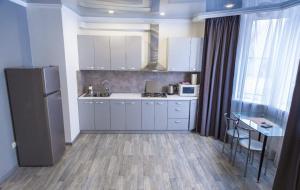 a kitchen with white cabinets and a table and a refrigerator at Cozy apartment in a new building close to the downtown in Kyiv