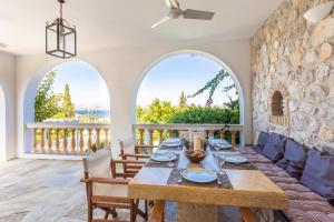 a dining room with a table and two arched windows at Villa Scirocco in Spetses