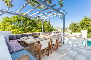 patio ze stołem i krzesłami oraz basenem w obiekcie Villa Scirocco w mieście Spetses