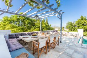 eine Terrasse mit einem Tisch, Stühlen und einem Pool in der Unterkunft Villa Scirocco in Spetses