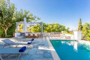 a swimming pool with chairs and a table at Villa Scirocco in Spetses