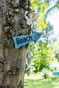 a sign that says beach hanging on a tree at Footprints House in Diani Beach