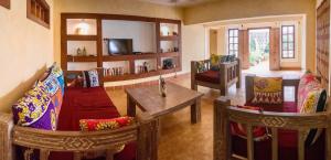 sala de estar con 2 sillas y mesa en Footprints House en Diani Beach