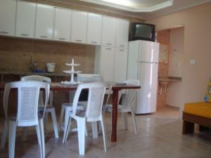 cocina con mesa, sillas y nevera en Budget Apartamento Na Praia Ubatuba, en Ubatuba