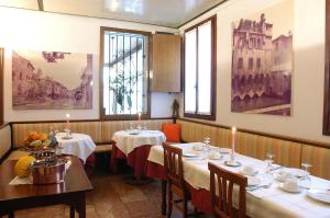 a dining room with two tables and two windows at Locanda Stella D'oro in Quinto di Treviso