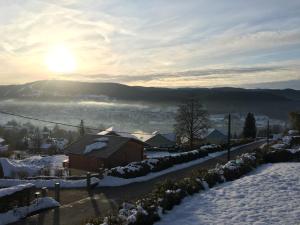a snow covered city with the sun in the distance at les charmes du lac Sauna et Spa in Gérardmer