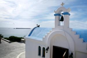 a white church with a blue roof and a bell at Saint George Hotel in Chrissi Akti