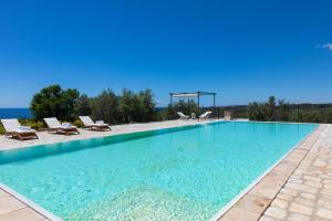 una piscina con sedie e l'oceano sullo sfondo di Tenuta Regina a Castrignano del Capo